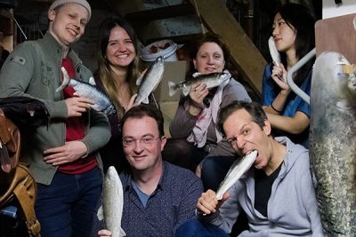 Sechs Musiker:innen mit Fischen in den Händen